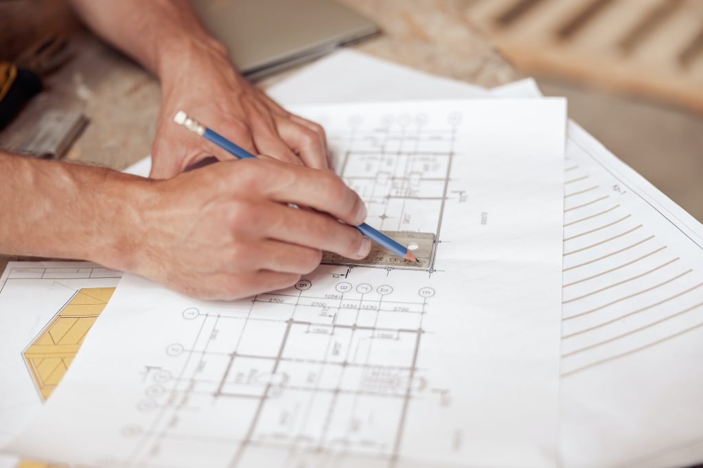 Mãos de arquiteto masculino a desenhar um plano arquitetónico de um edifício